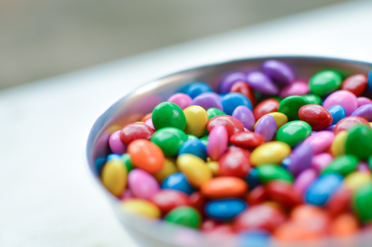 Vibrant close-up of assorted candy-coated chocolates in a silver bowl.